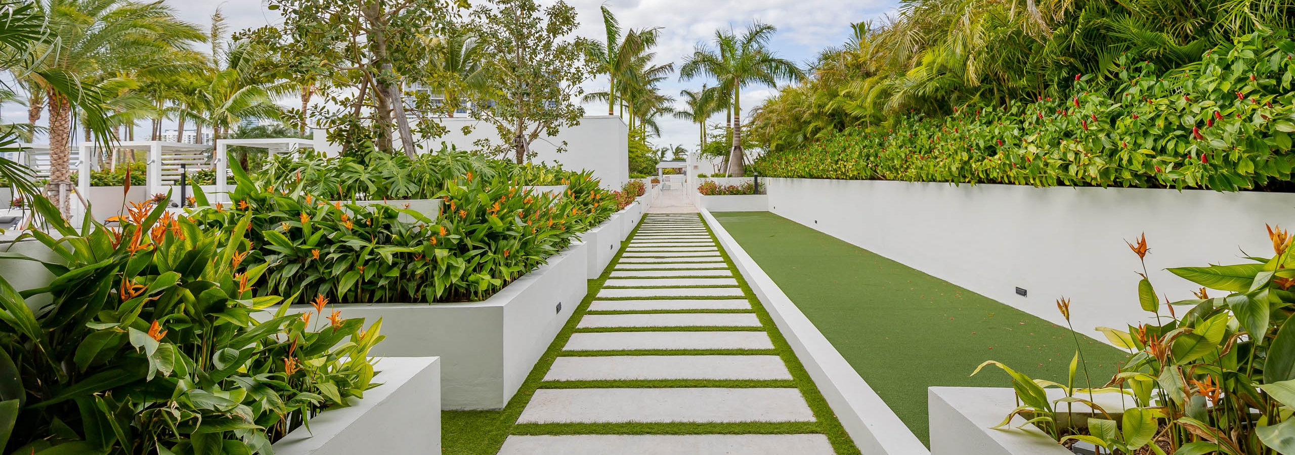 AMLI Midtown Miami apartments courtyard with a faux grass pathway and stepping pavers with lush landscape and planter boxes