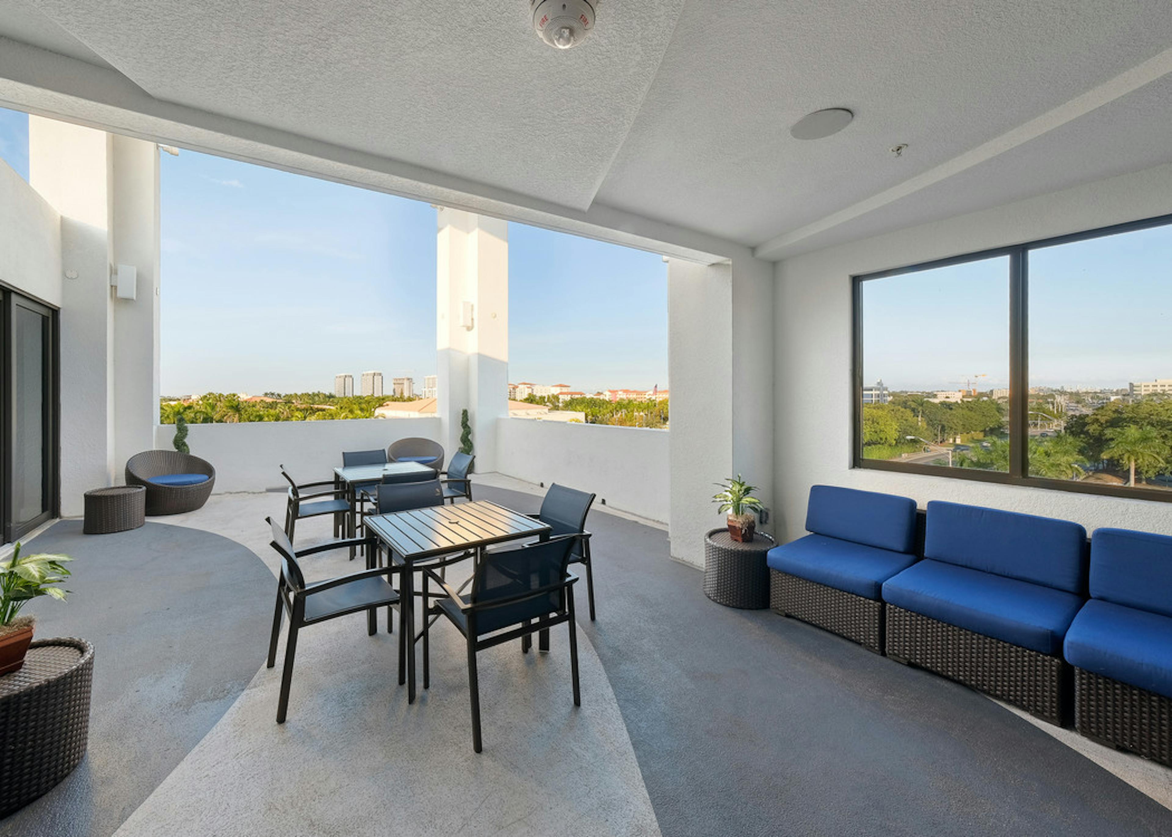 AMLI 8800 exterior skyline view of the rooftop terrace with table and chairs and blue sofa seating area