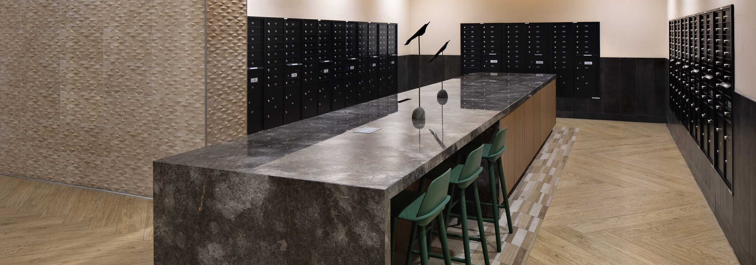 Mail room at AML Park Broadway apartment building with a long sleek quartz counter surrounded by black mailboxes