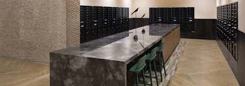 Mail room at AML Park Broadway apartment building with a long sleek quartz counter surrounded by black mailboxes