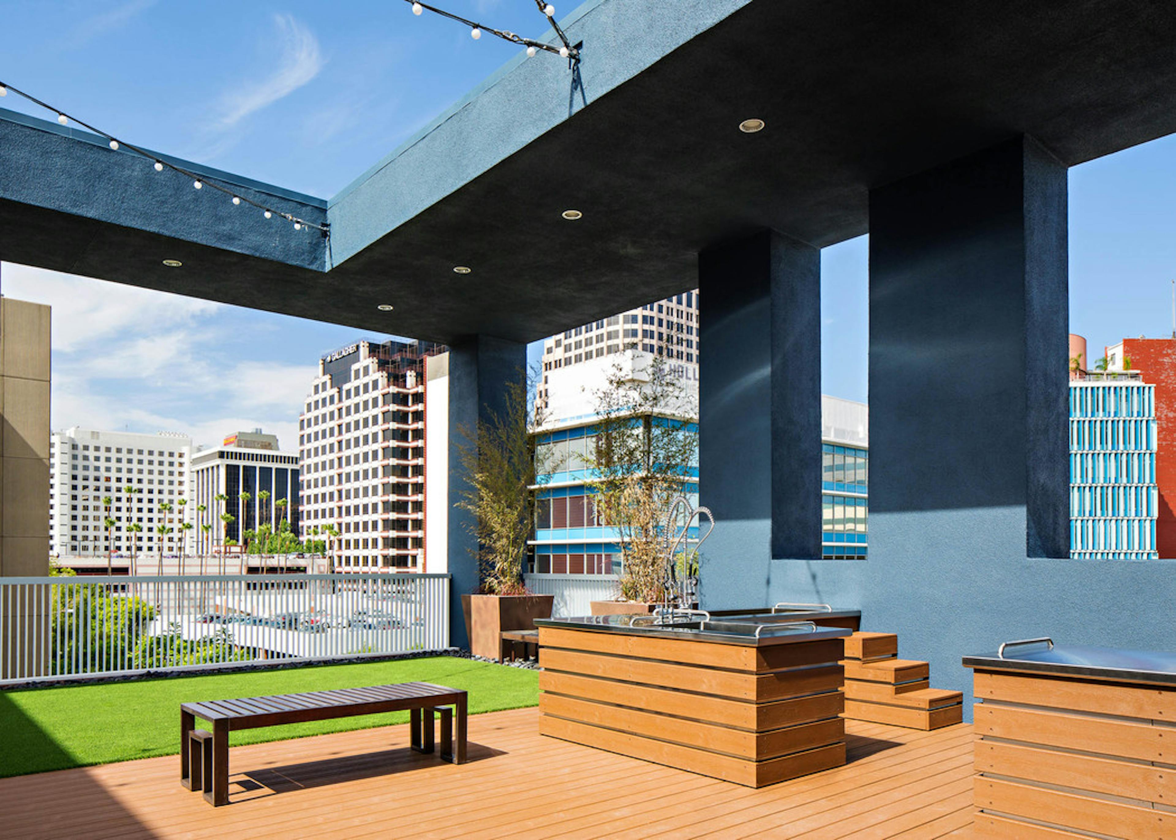 Daytime view of Rooftop pet park with dog spa overlooking the city at AMLI Lex on Orange apartments with turf rug and bench