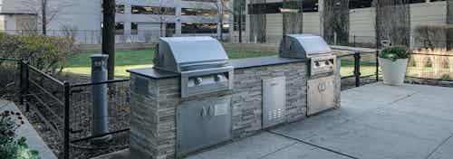 Stainless grilling station at AMLI 900 apartments with greenery and a view of two parking structures in the background