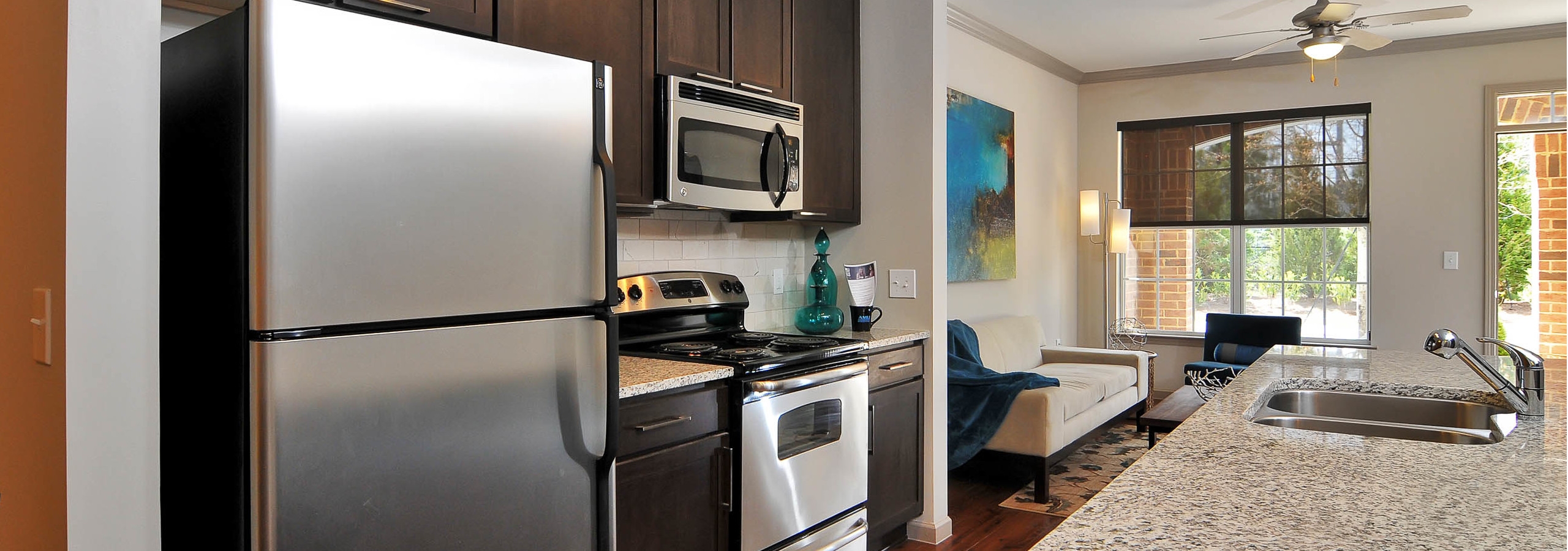 Kitchen at AMLI North Point with dark cabinets and stainless steel appliances and an island which connects to living space