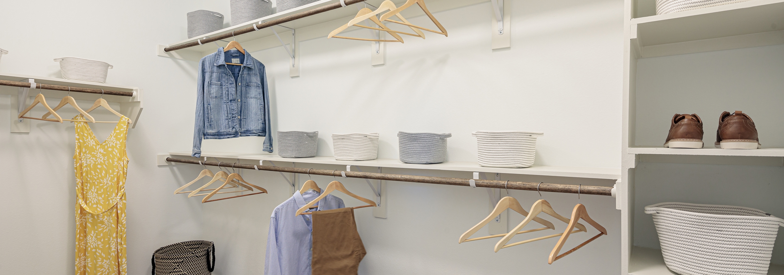 Interior of walk in closet at AMLI Addison with built in shelving of varying heights with wooden hangers for clothing