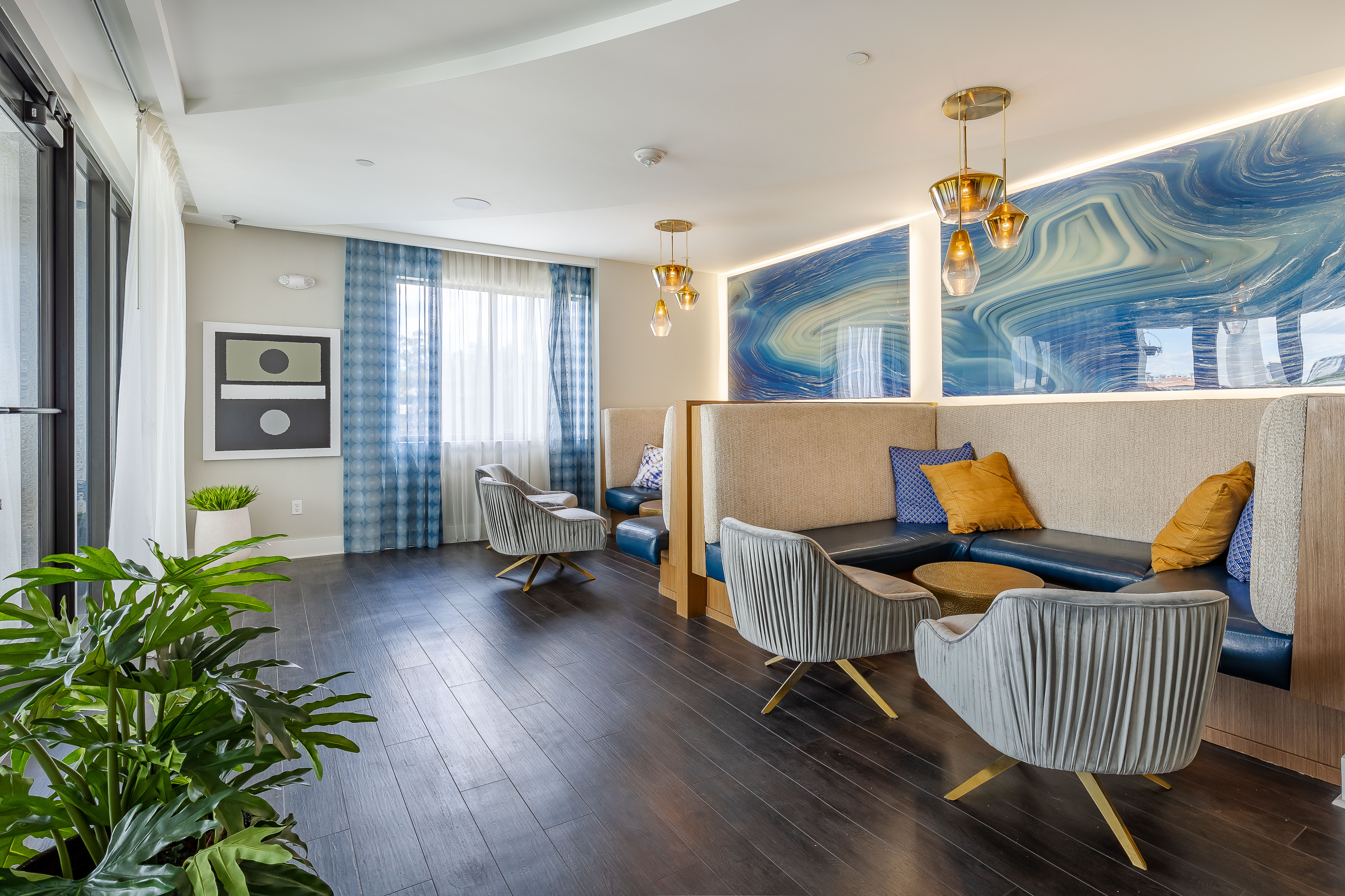 The AMLI 8800 apartment resident sky lounge with wood floors and booth seating with blue geode walls and gold chandeliers 