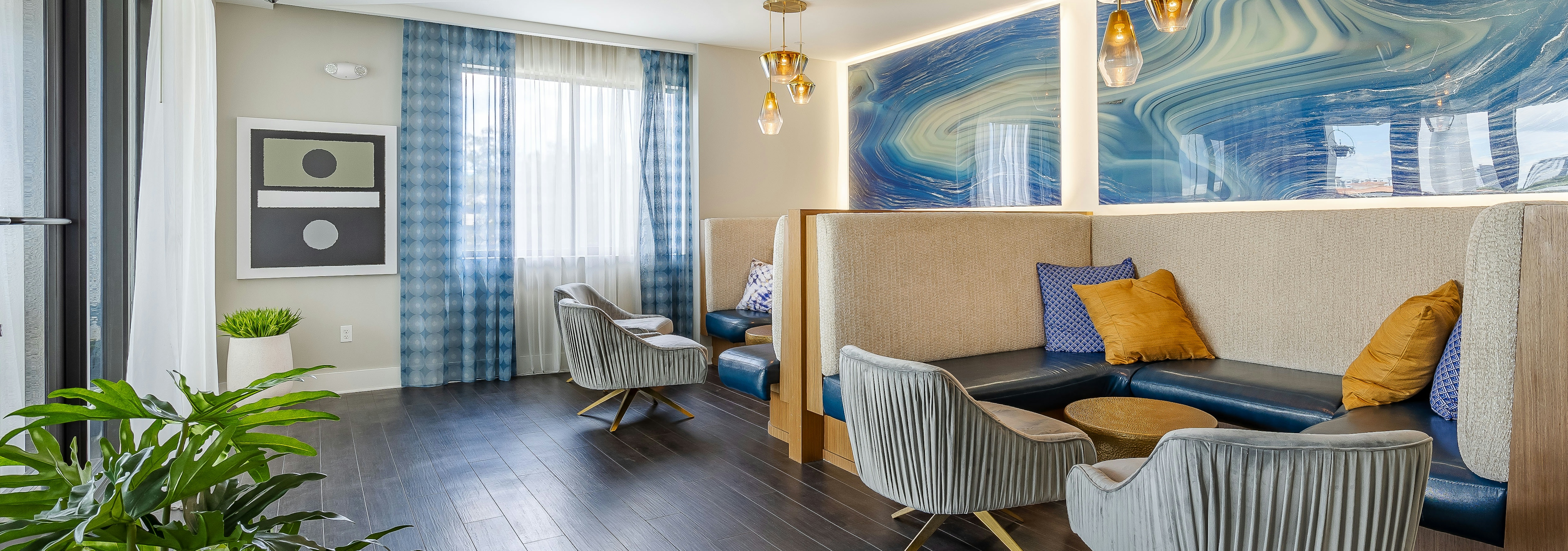 The AMLI 8800 apartment resident sky lounge with wood floors and booth seating with blue geode walls and gold chandeliers