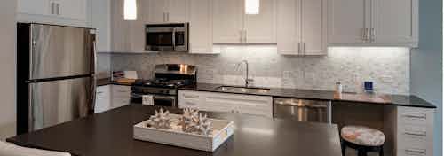 AMLI Deerfield apartment kitchen with dark countertops and white cabinets with stainless steel appliances and an island