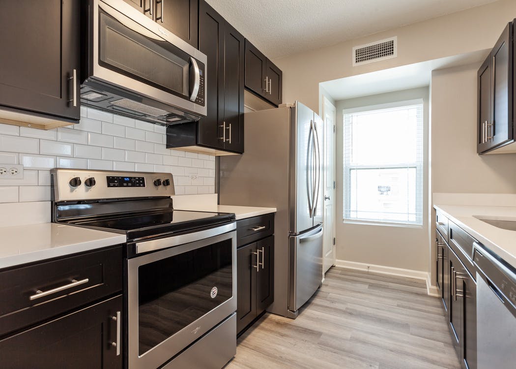 Kitchen at AMLI at Seven Bridges with stainless steel appliances and dark cabinetry, white tile backplash and hard wood floor