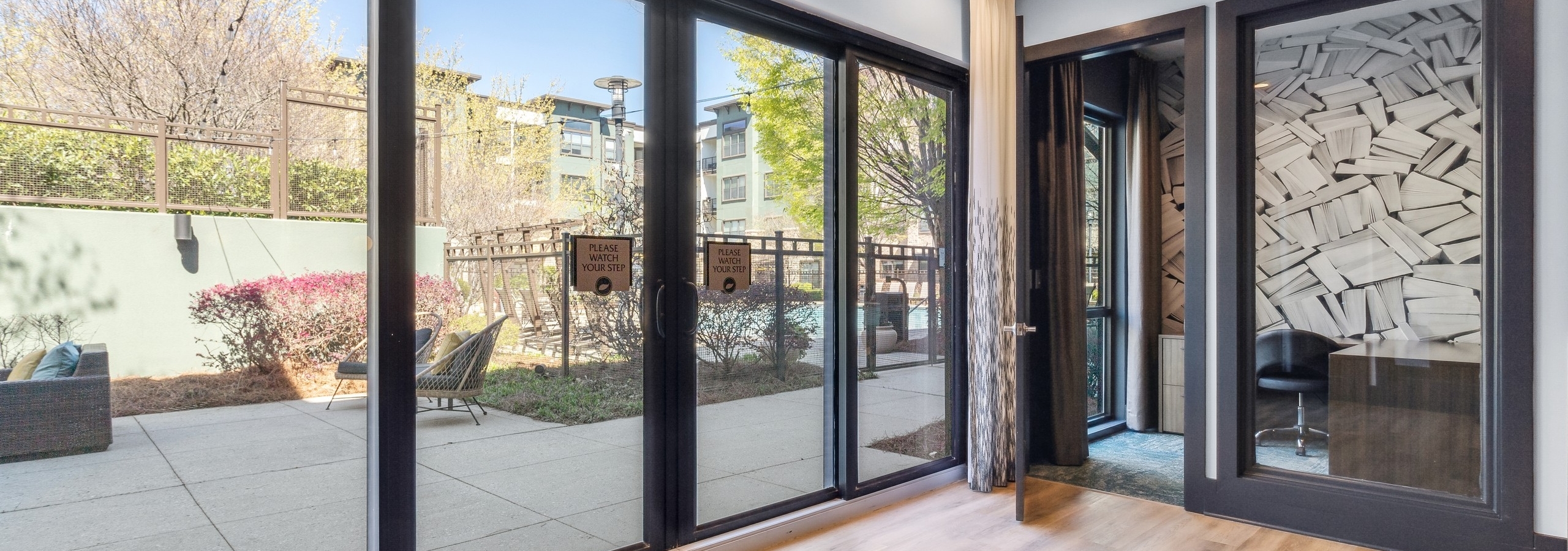 AMLI Parkside private office with glass wall and open door adjacent to sliding glass doors overlooking furnished patio