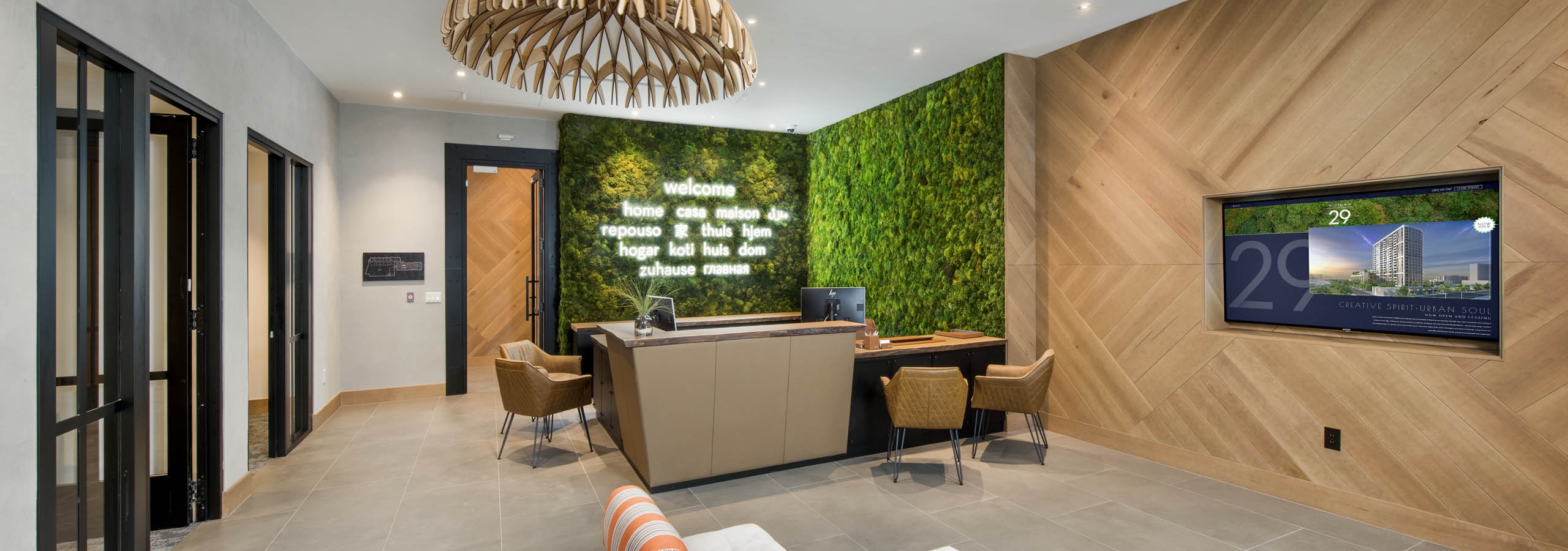 Leasing office at AMLI Midtown 29 with green living wall and neon signage and wooden light fixture over seating area with TV