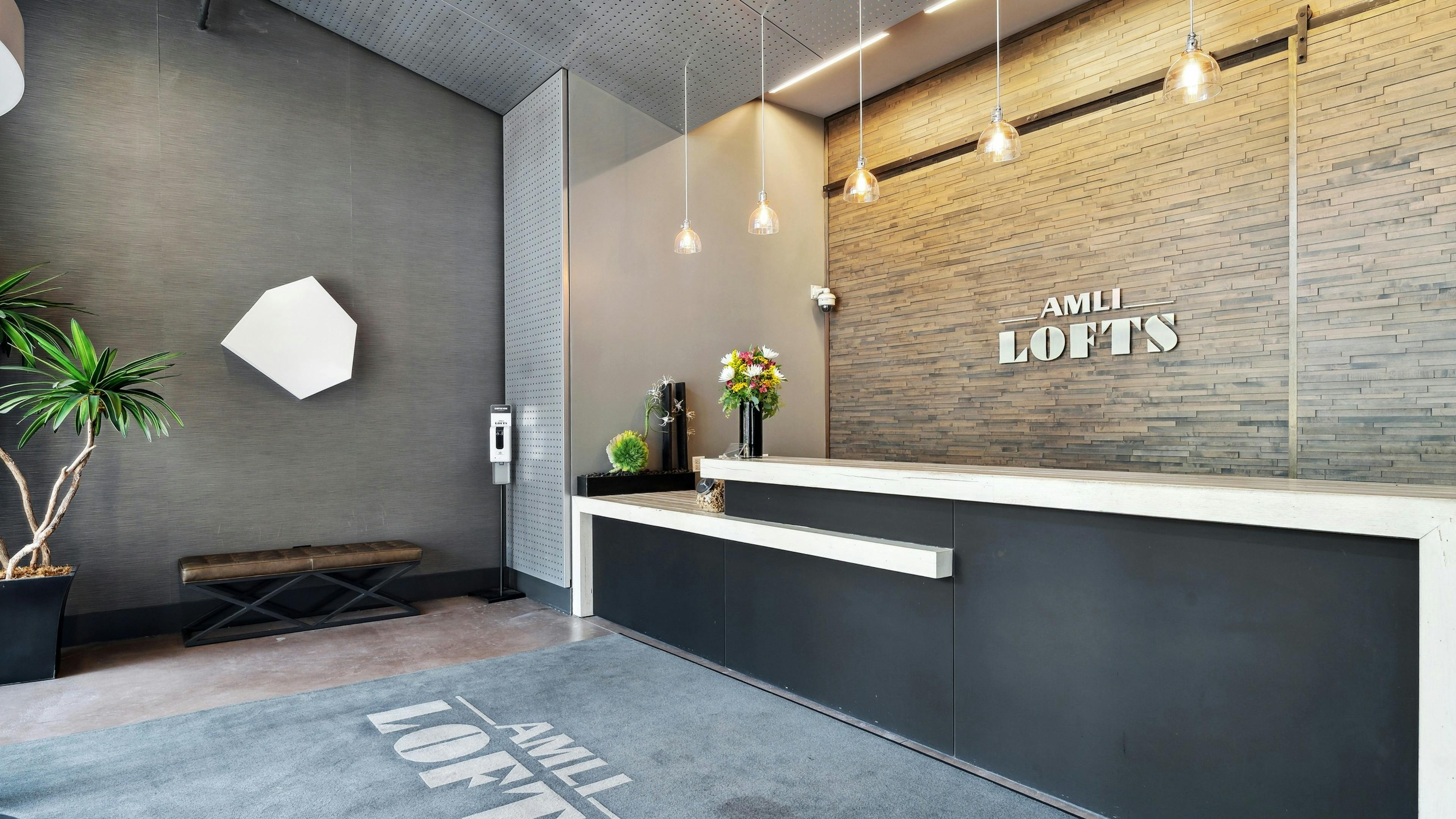 Interior view of the Clark lobby at AMLI Lofts which has a stone textured accent wall behind a modern black and white desk