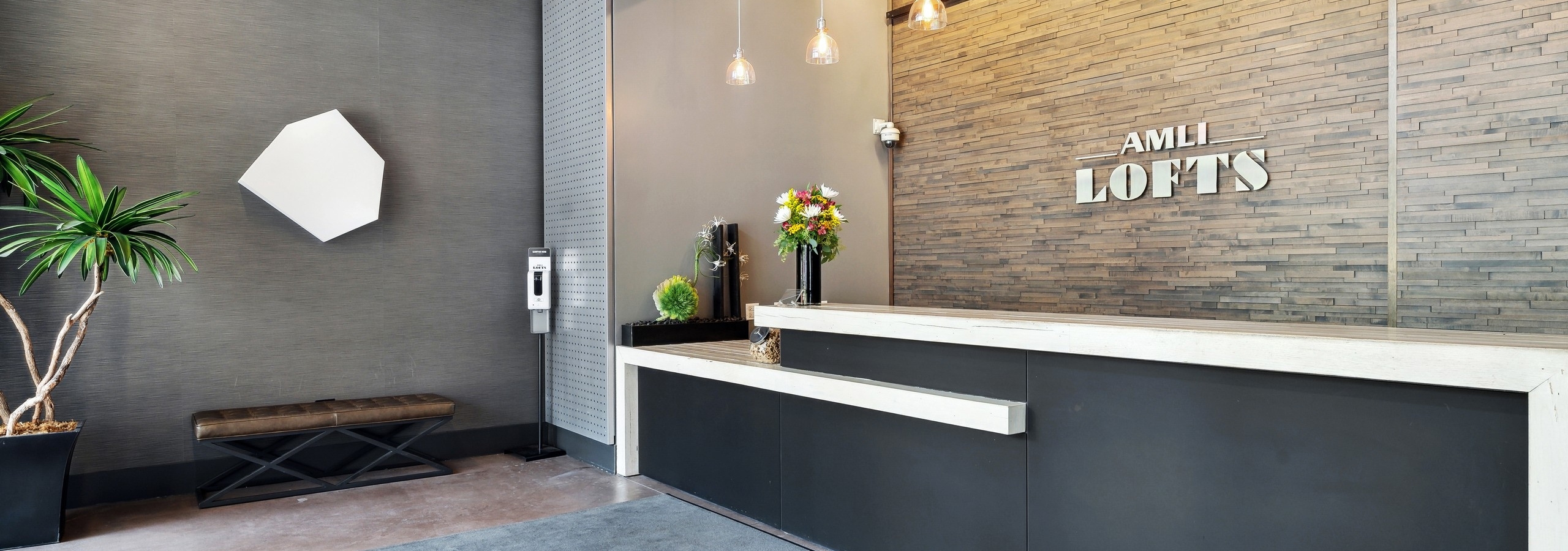 Interior view of the Clark lobby at AMLI Lofts which has a stone textured accent wall behind a modern black and white desk