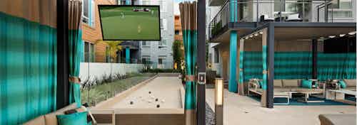 Daytime view of AMLI Uptown Orange curtained cabanas with individual large screen TVs overlooking the bocce ball court