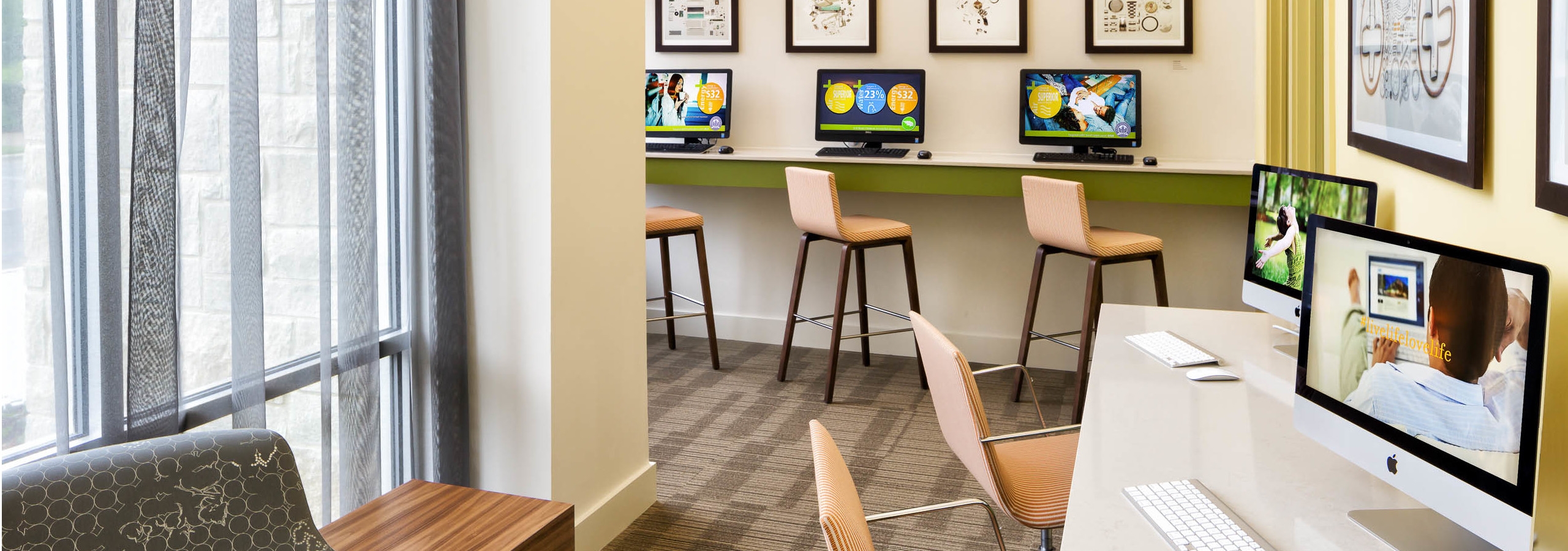 AMLI at Mueller business center with bar stools at a raised counter with desktop computers and light flooring with tall windows