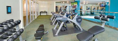 Alternate angle of AMLI North Point fitness center with a dumbbell rack and bench across a line of exercise machines