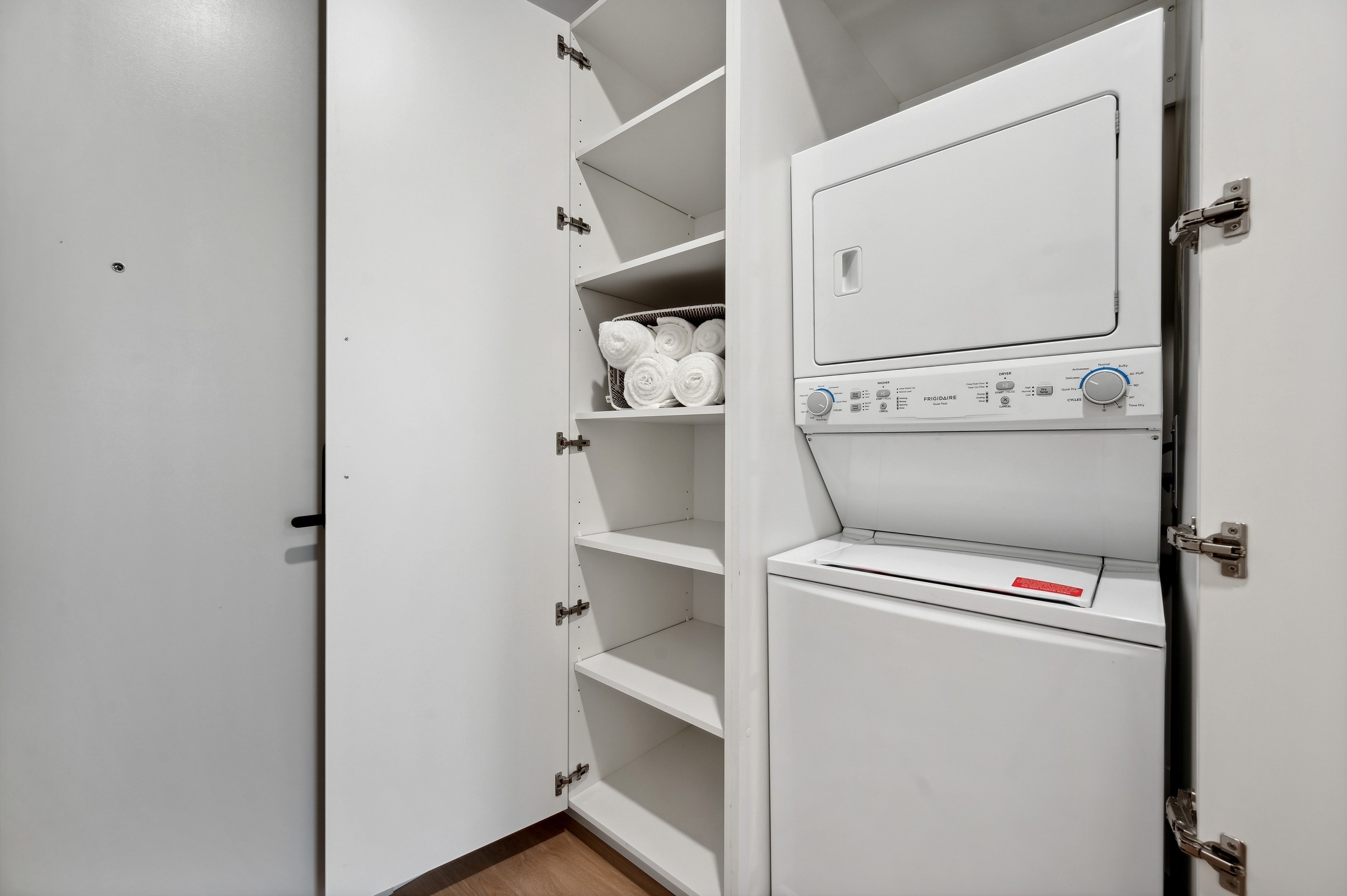 White stacked washer and dryer with open white linen closet with rolled white towels at AMLI 808 apartments