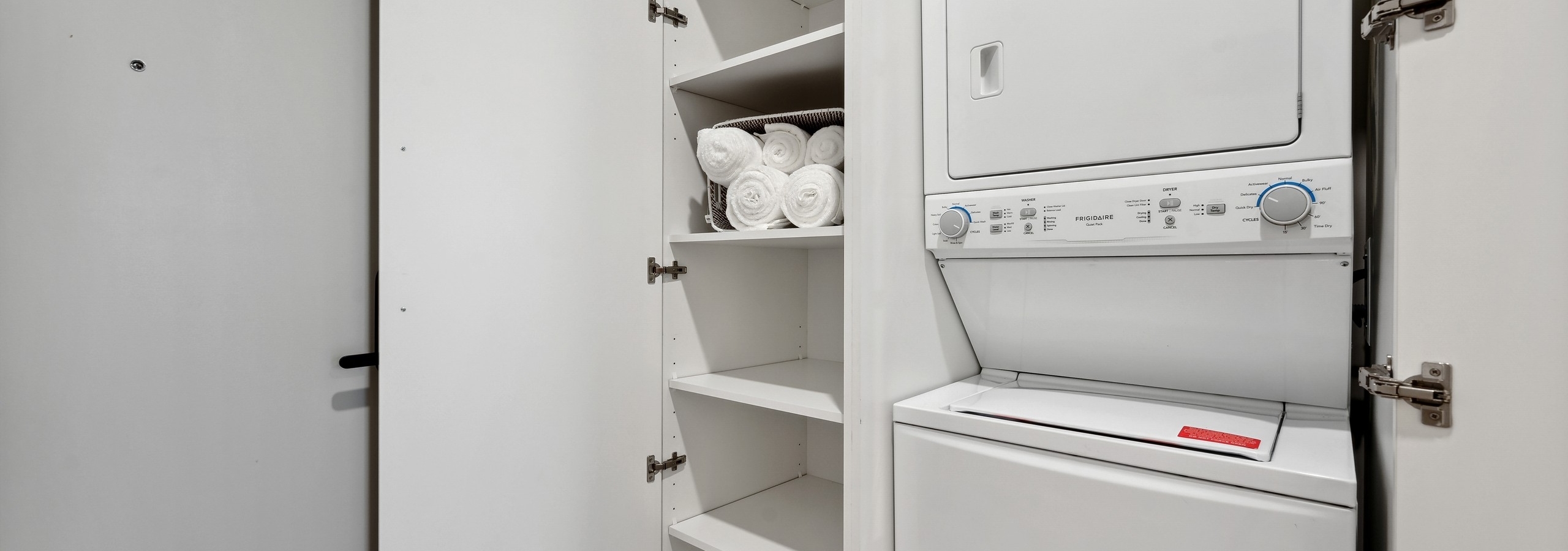 White stacked washer and dryer with open white linen closet with rolled white towels at AMLI 808 apartments