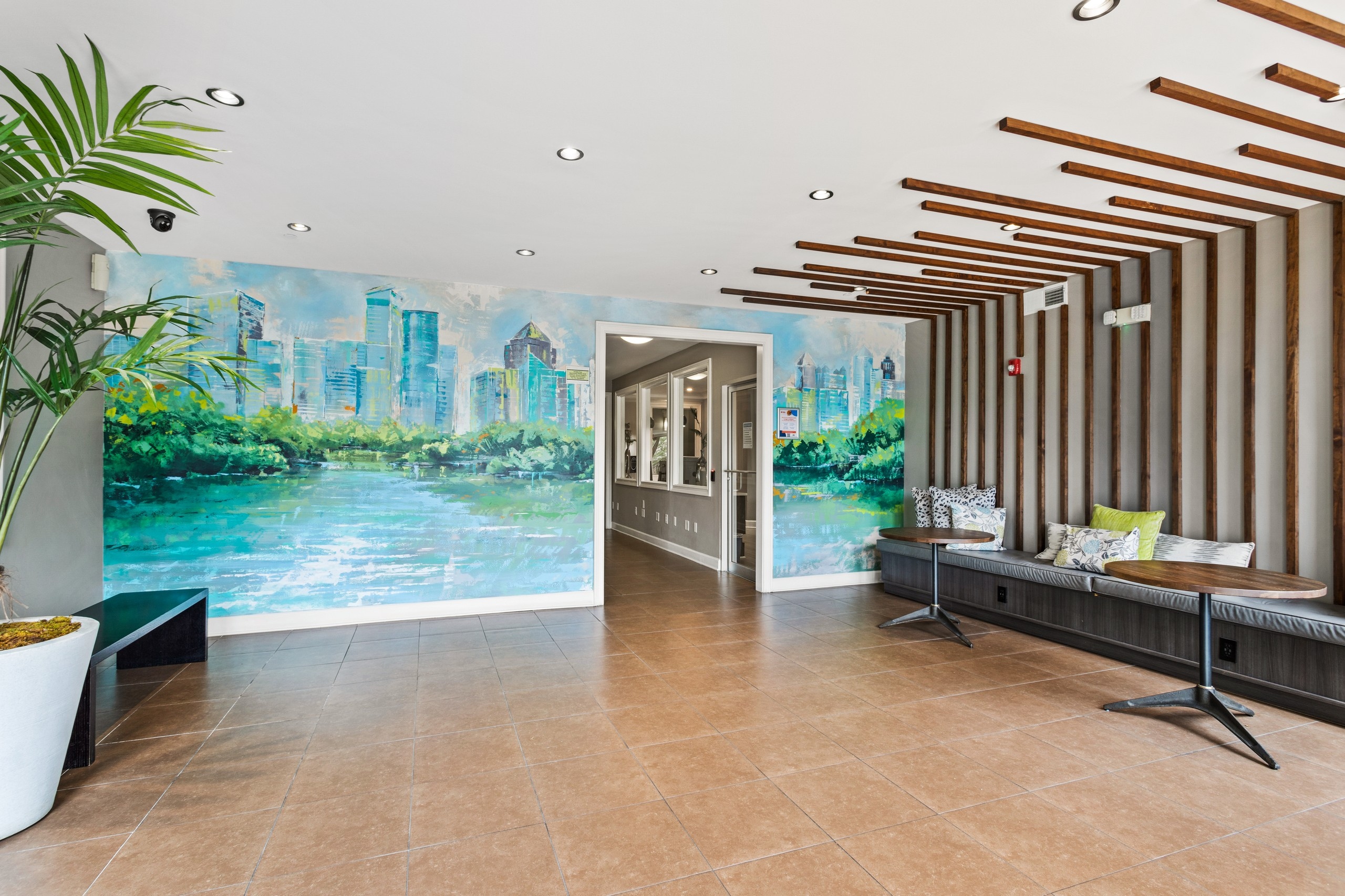 Lobby area with a colorful mural of the city and wood panels and booth on adjacent wall at AMLI Lindbergh apartments
