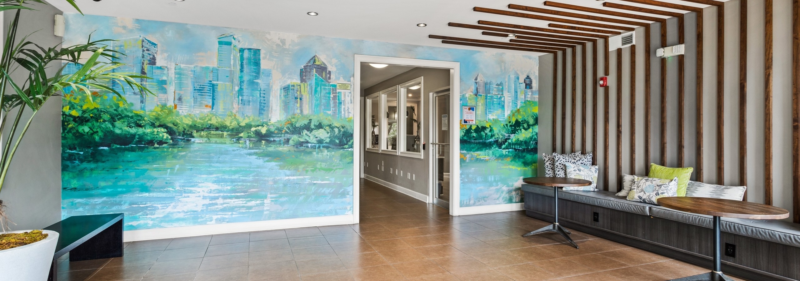 Lobby area with a colorful mural of the city and wood panels and booth on adjacent wall at AMLI Lindbergh apartments