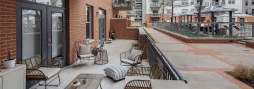 AMLI Downtown oversized poolside resident patio with brown wicker furniture and gray cement flooring beside red brick building