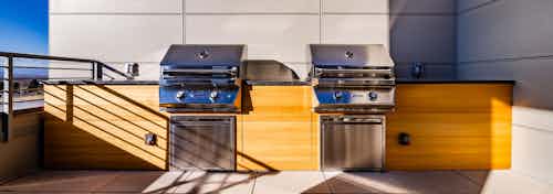 Daytime view of outdoor rooftop lounge with two stainless steel barbecue stations at AMLI Littleton Village apartments
