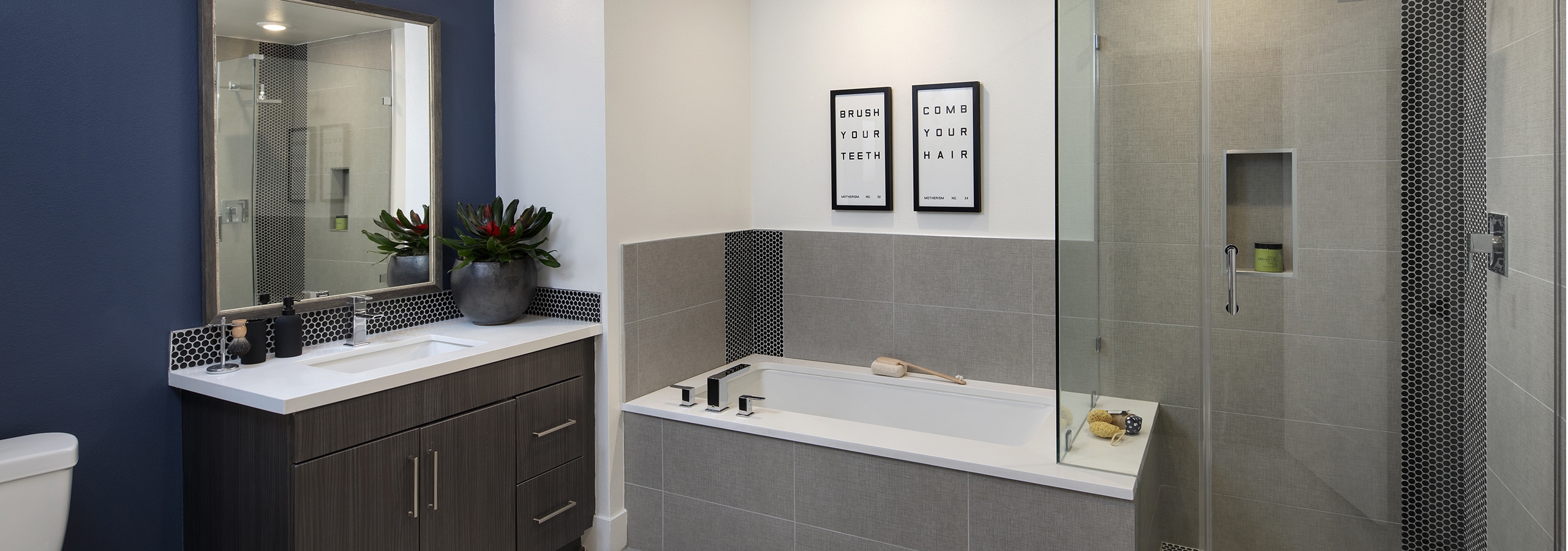 Interior of AMLI Marina Del Rey apartment bathroom with free standing shower with frameless doors and tub and tile surround