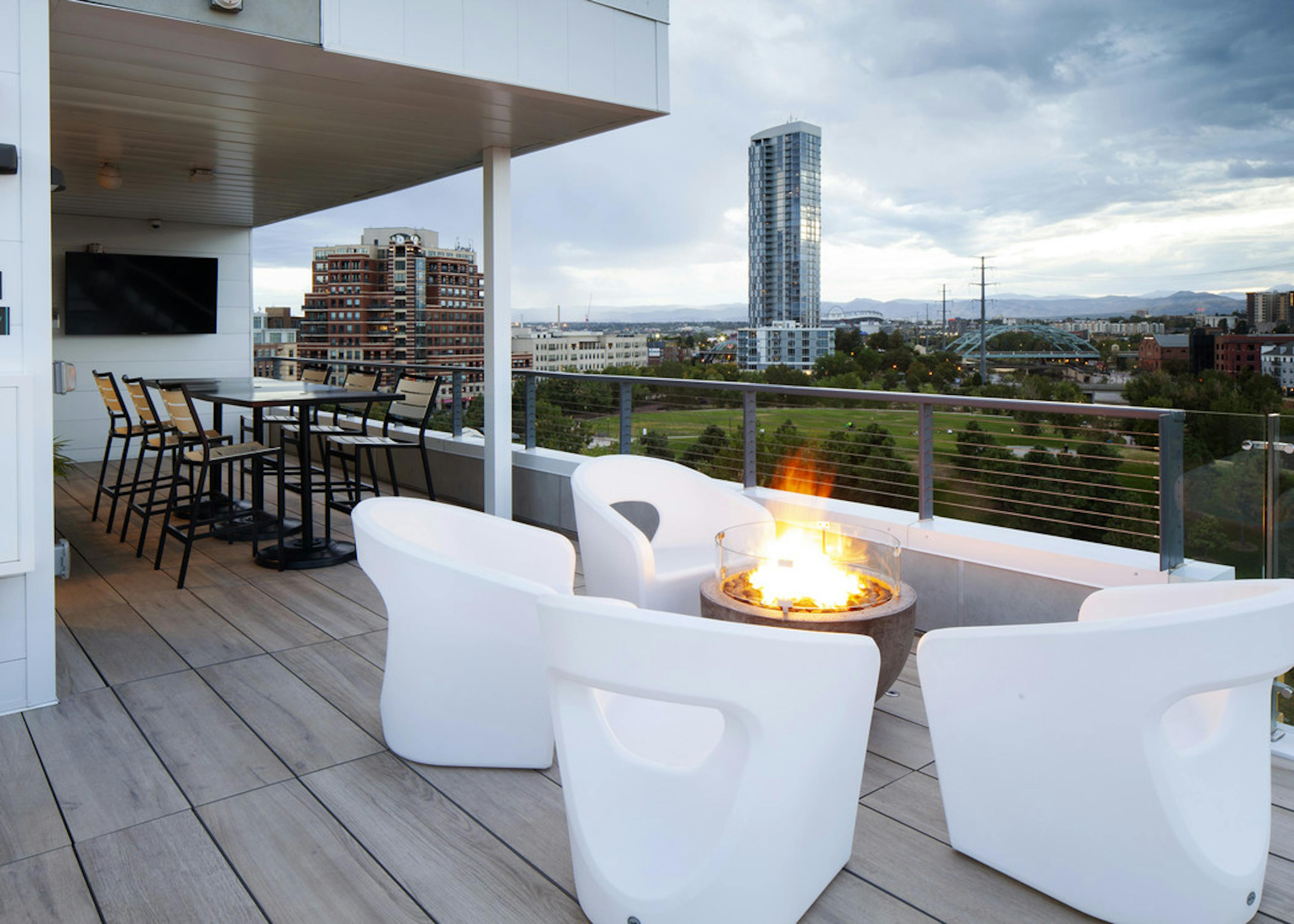 An exterior view of AMLI Riverfront Green roof top deck with fire pit and furniture and mountain view and sky scraper views