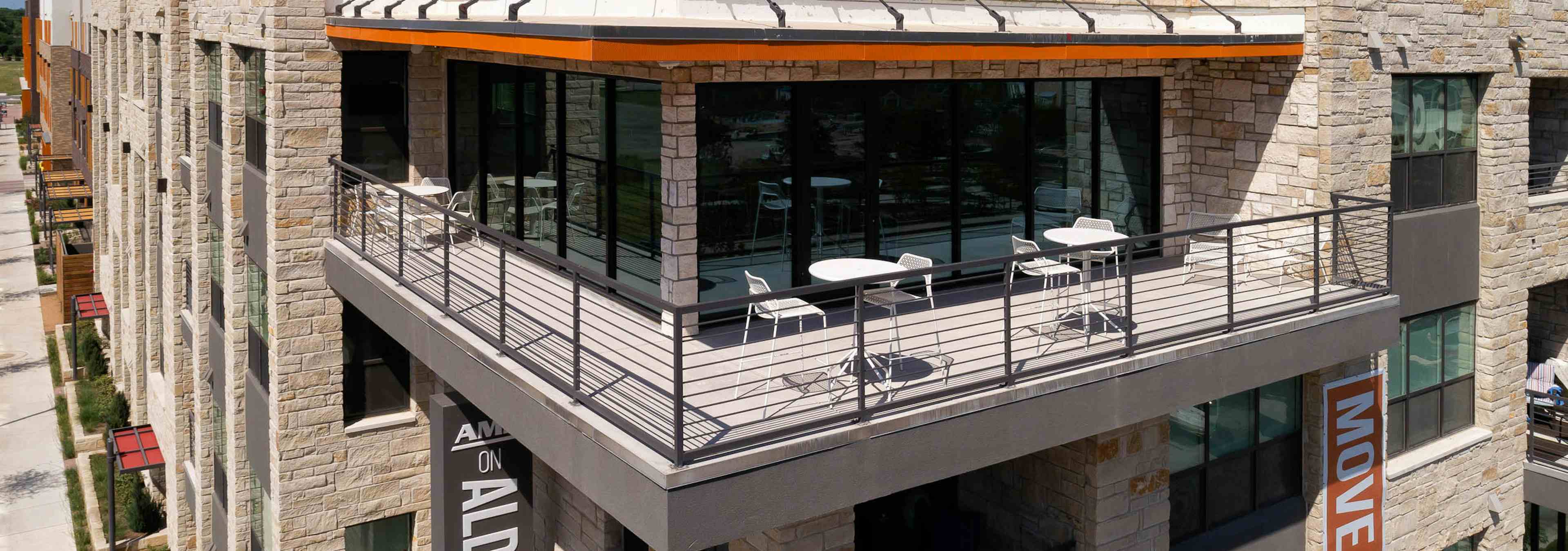 Exterior daytime view of rooftop balcony at AMLI on Aldrich apartment community with outdoor tables and chairs