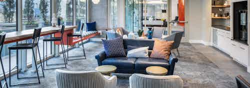 AMLI Arts Center clubroom with grey and blue seating and a white entertainment center with barstools facing tall windows