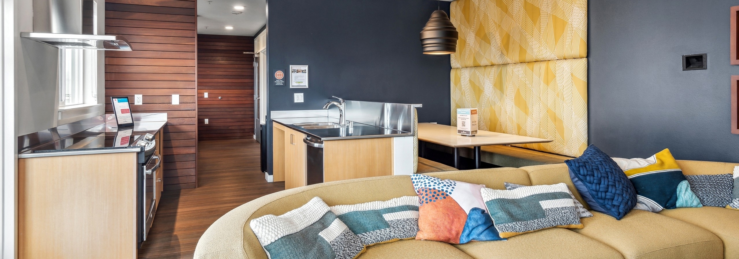 Interior view of a sky lounge at AMLI Wallingford with a couch in front of a kitchen area with stainless sink