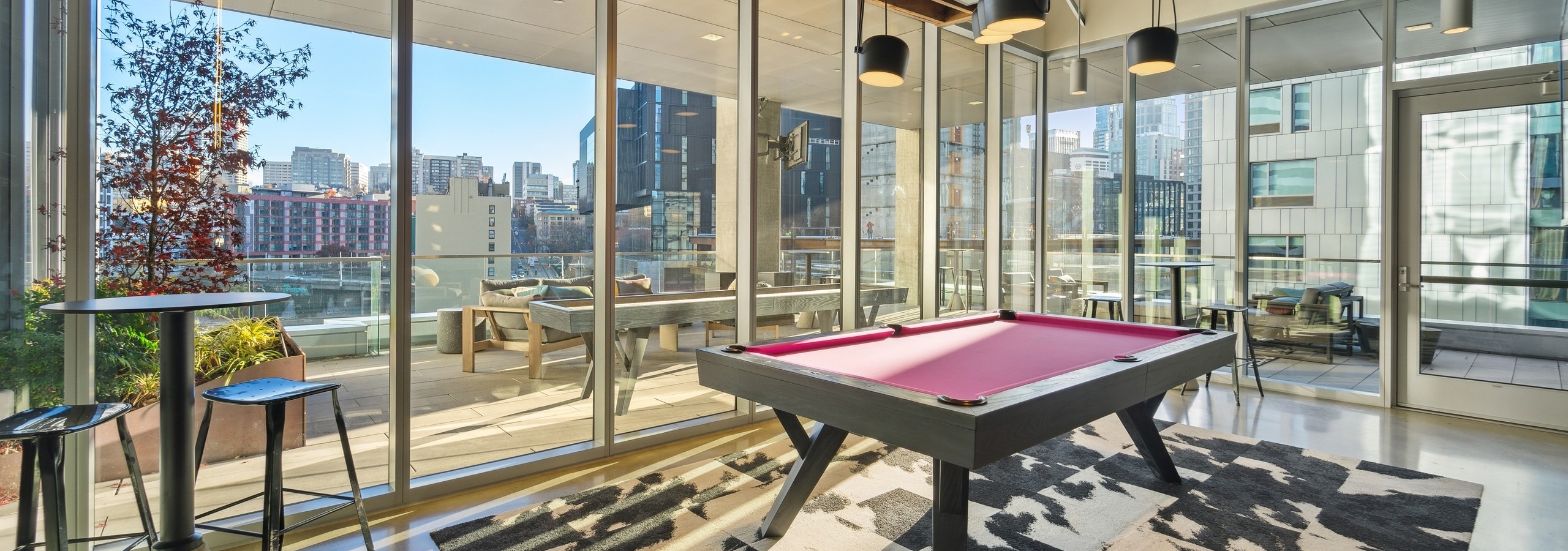 Interior view of a rooftop resident lounge at AMLI Arc with a billiards table and two high top seating tables with stools