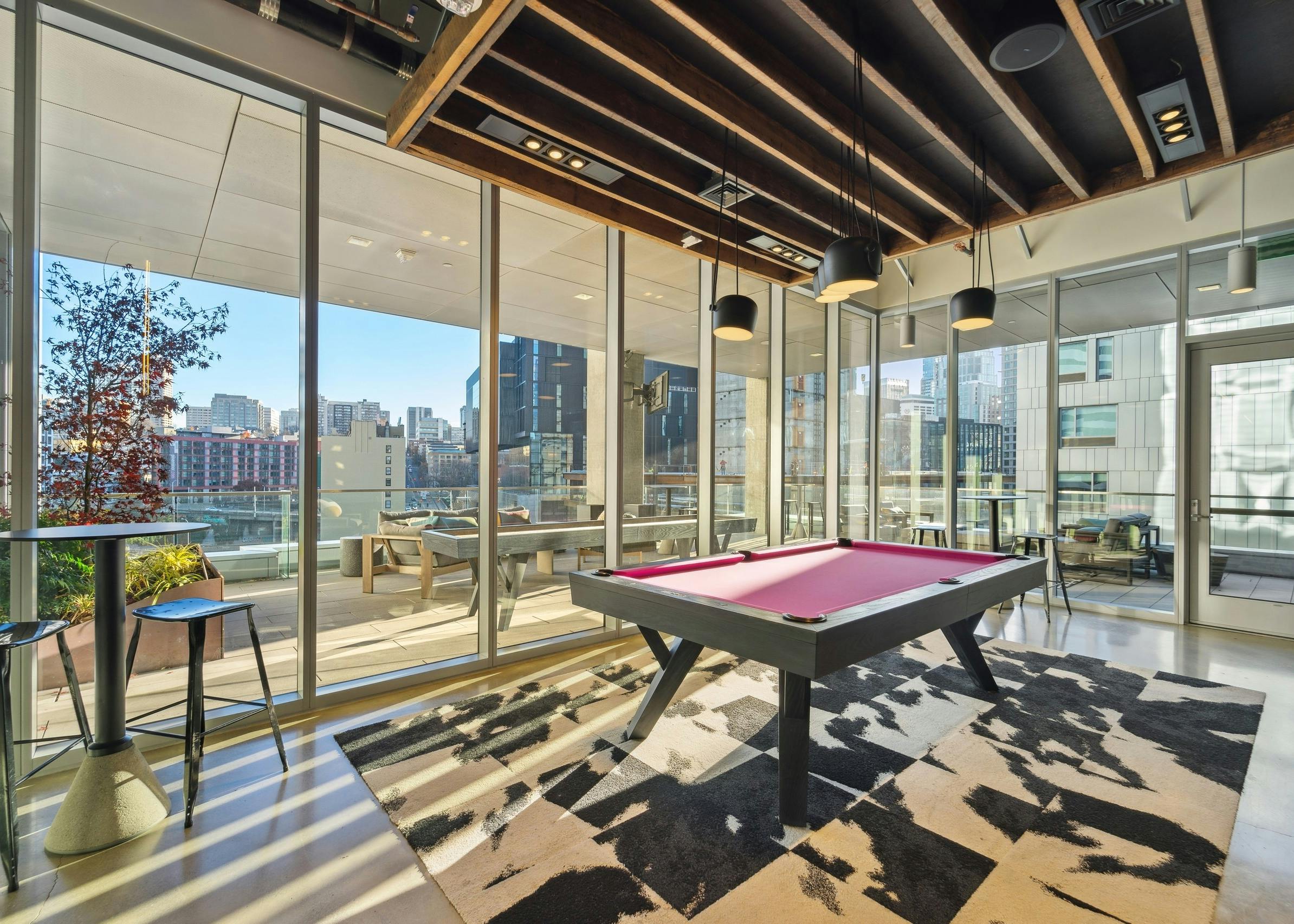 Interior view of a rooftop resident lounge at AMLI Arc with a billiards table and two high top seating tables with stools