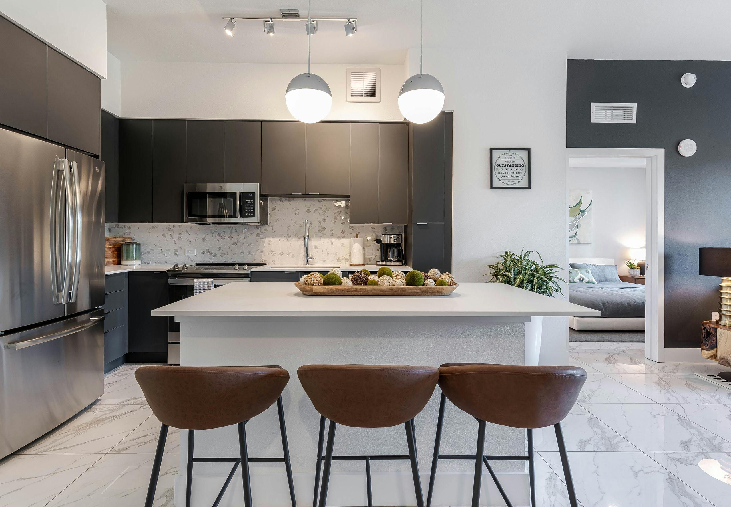 AMLI Park West apartment kitchen with dark cabinetry and stainless appliances and white island with wood decorative tray