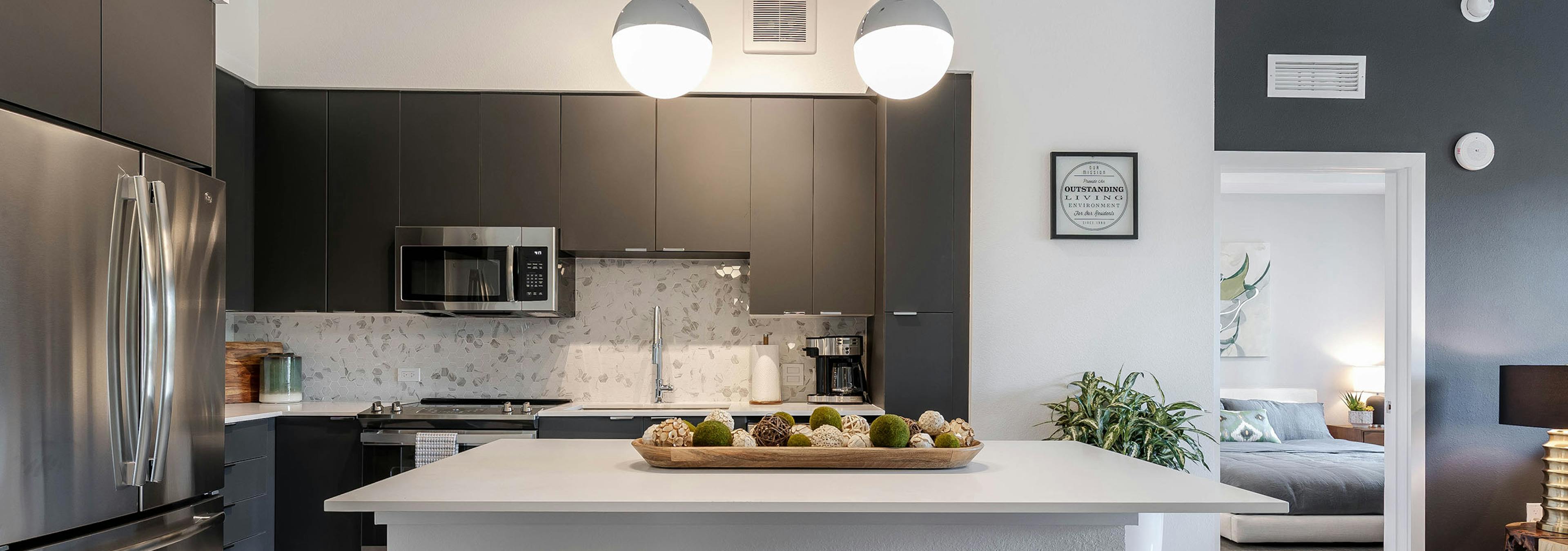 AMLI Park West apartment kitchen with dark cabinetry and stainless appliances and white island with wood decorative tray 