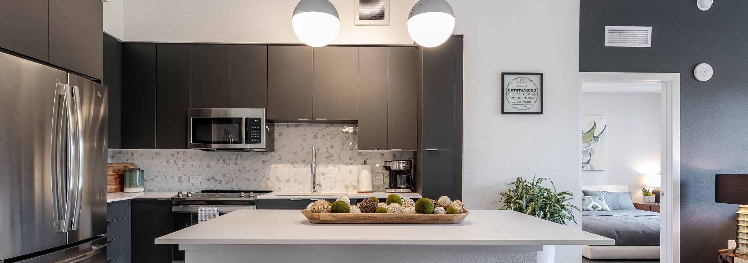 AMLI Park West apartment kitchen with dark cabinetry and stainless appliances and white island with wood decorative tray