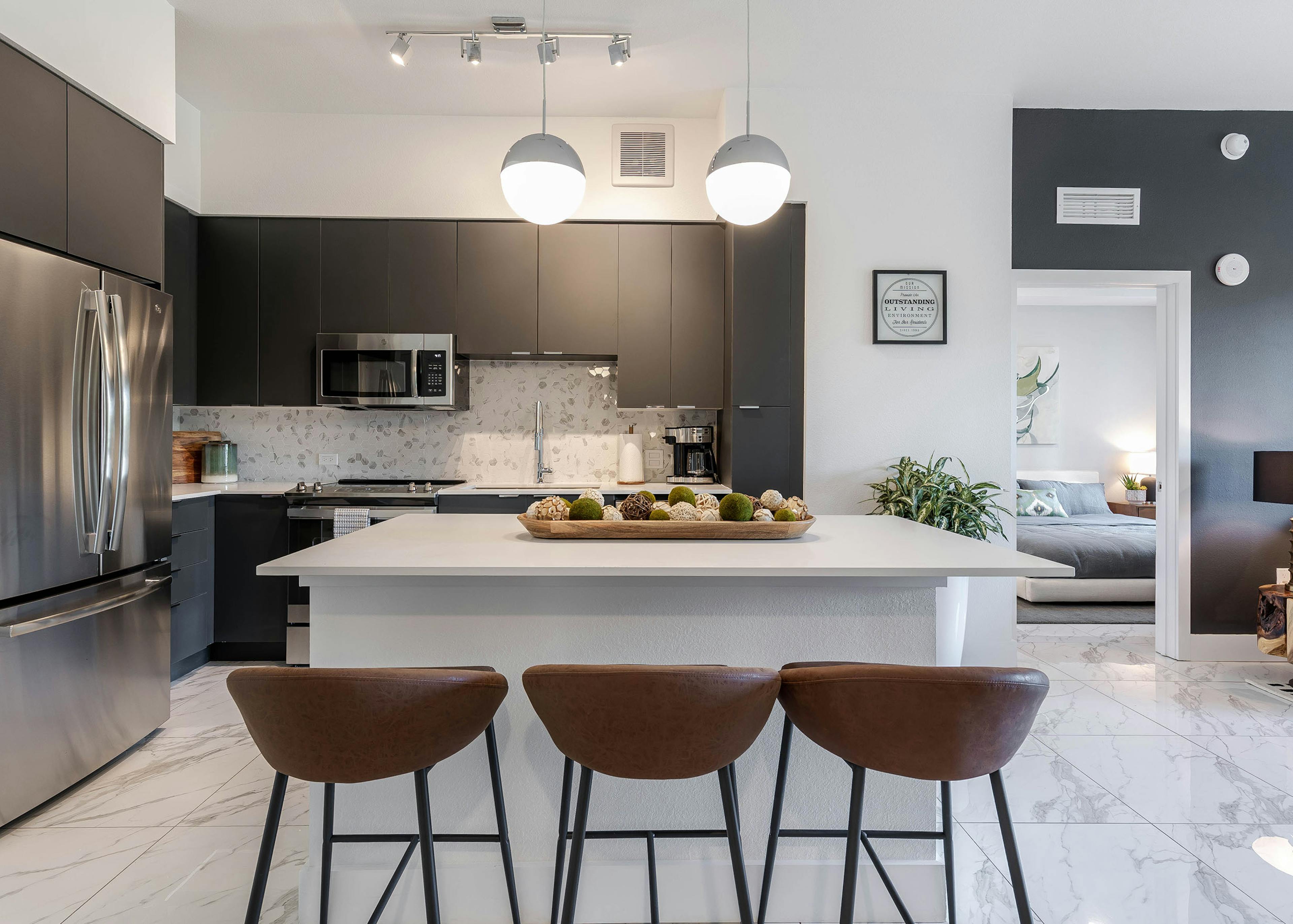 AMLI Park West apartment kitchen with dark cabinetry and stainless appliances and white island with wood decorative tray 