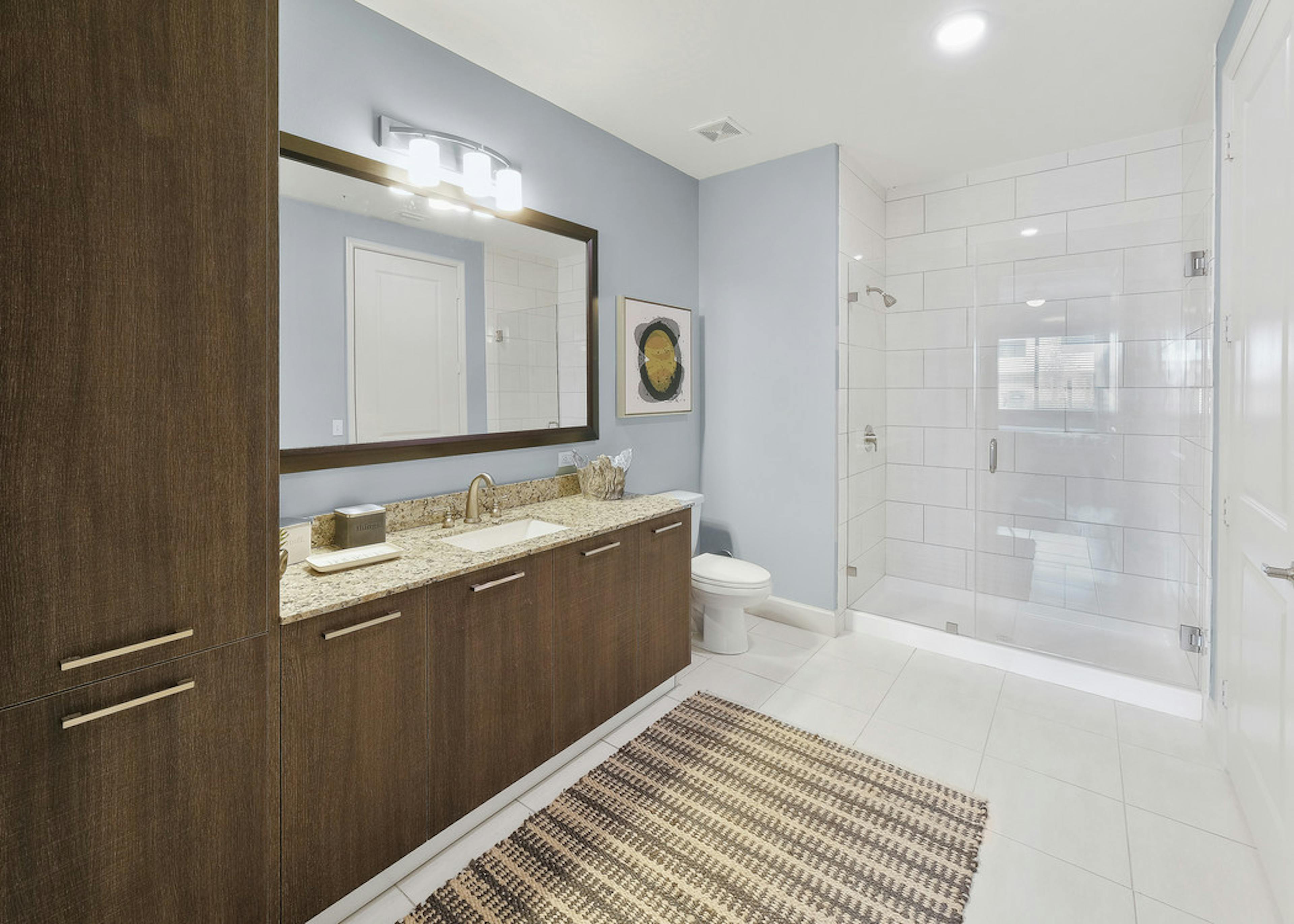  AMLI 8800 apartment bathroom with large single sink vanity, mirror, toilet and stand up glass enclosed shower