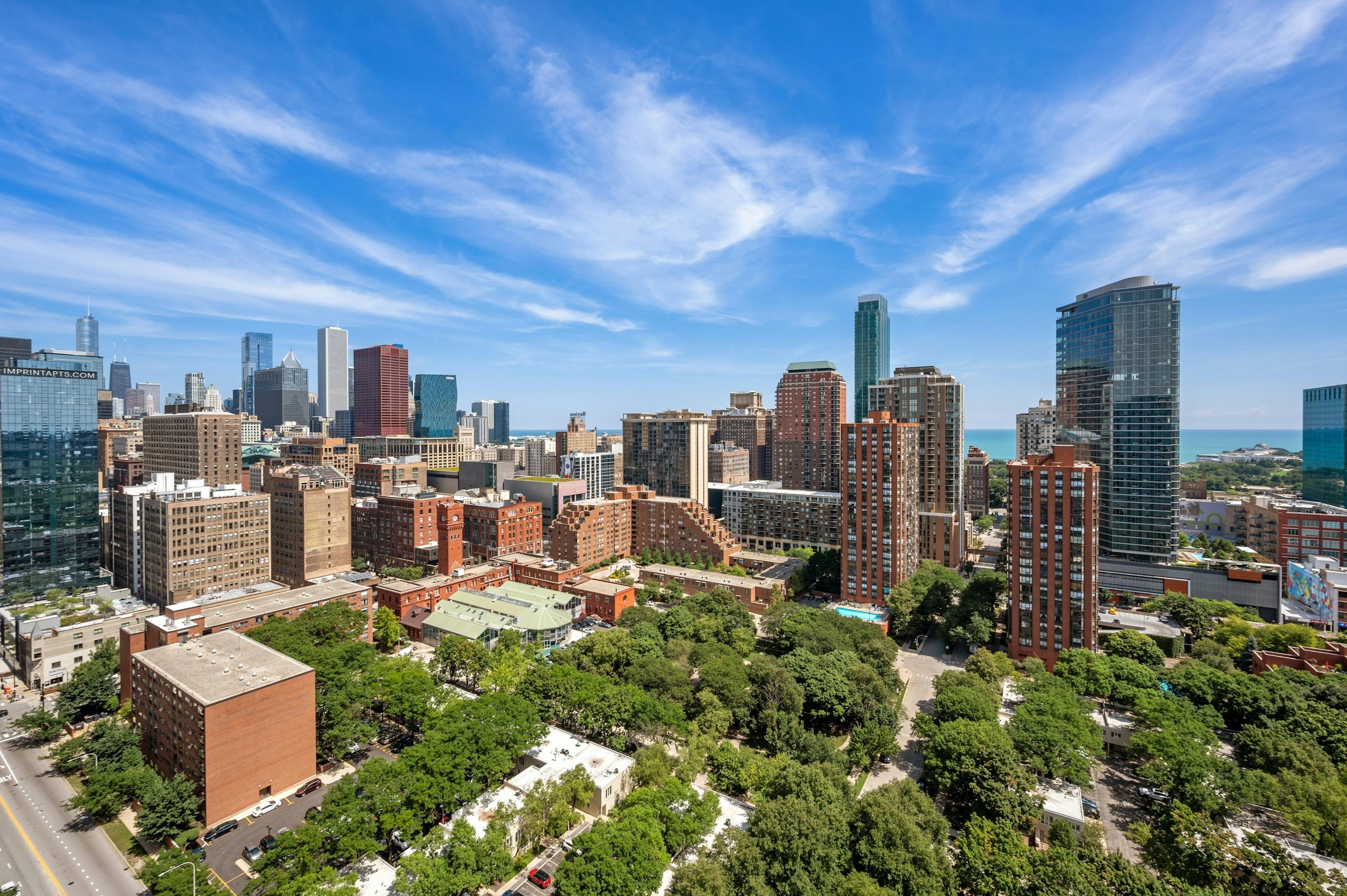 View of the city from AMLI 900 rooftop with city buildings and green trees and blue sky with wispy clouds