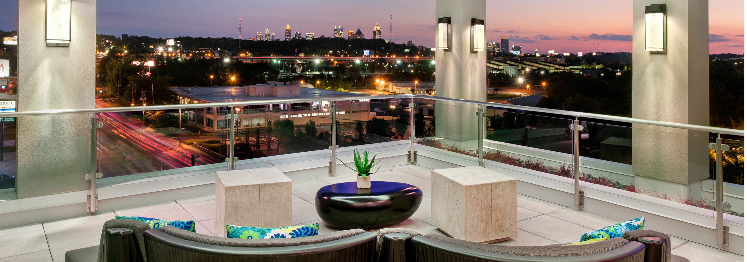 Nighttime exterior shot of AMLI Piedmont Heights sky deck with various couch seating to overlook lit up Atlanta skyline