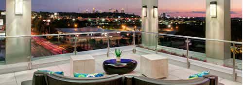 Nighttime exterior shot of AMLI Piedmont Heights sky deck with various couch seating to overlook lit up Atlanta skyline