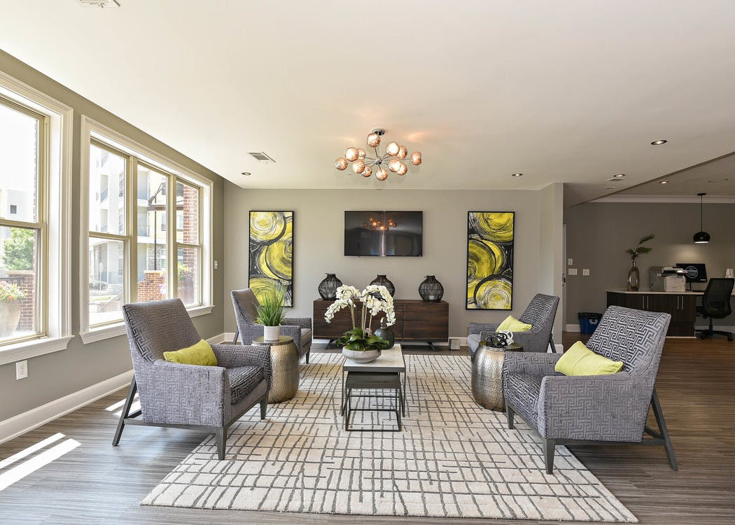 AMLI Lindbergh resident lounge with four patterned chairs and yellow decor accents with large windows facing landscape
