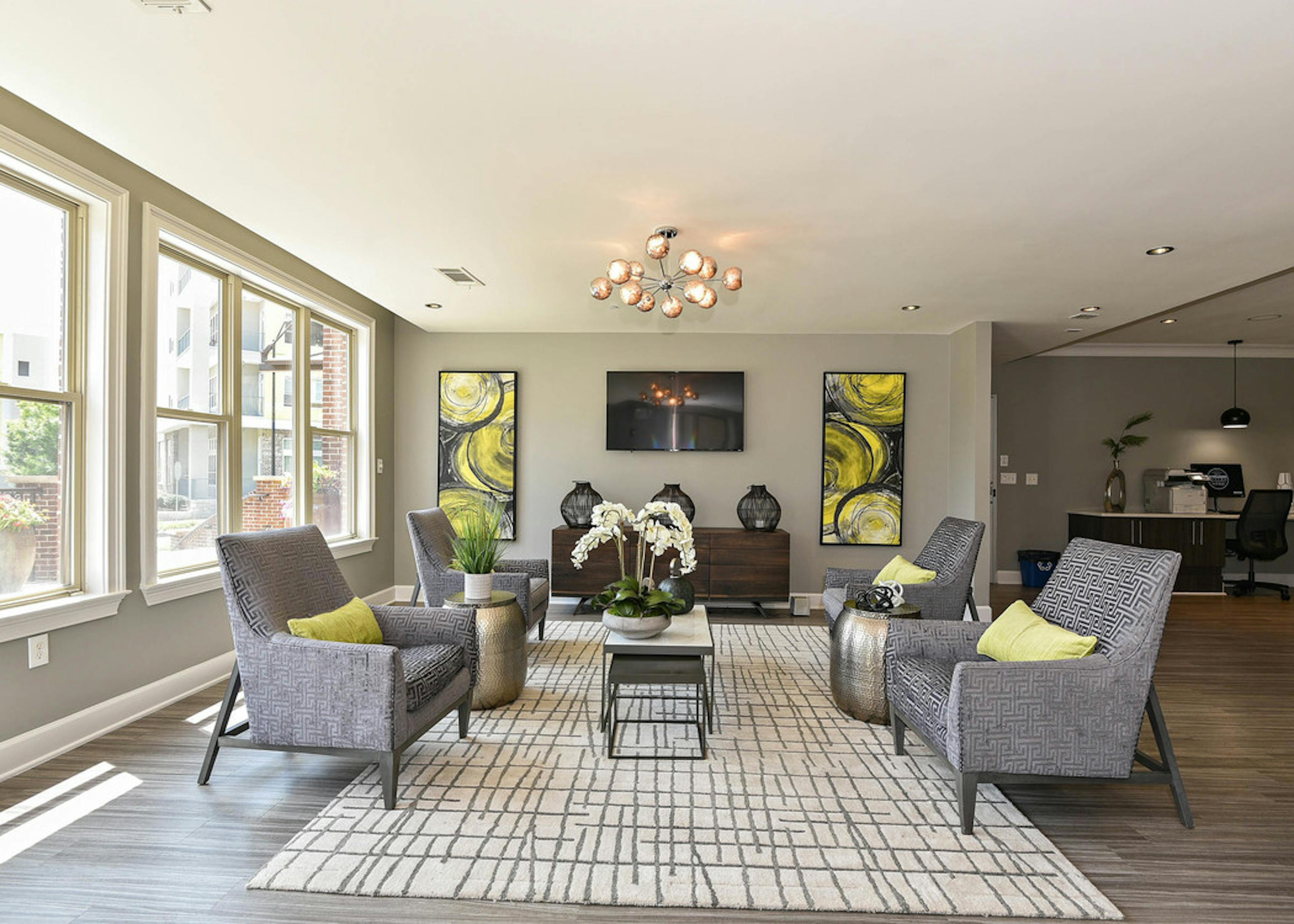 AMLI Lindbergh resident lounge with four patterned chairs and yellow decor accents with large windows facing landscape