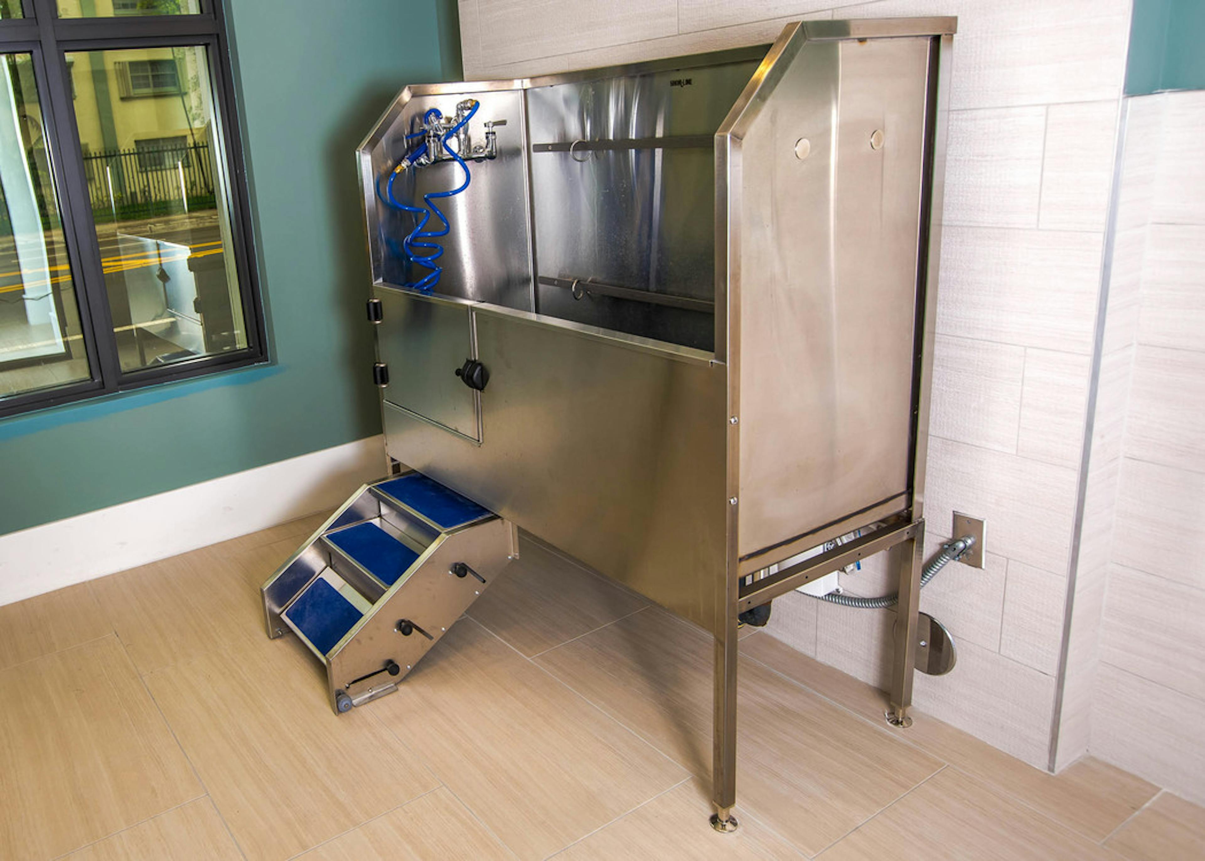 Interior view of the paw wash at AMLI Joya with large stainless steel tub, walk up ramp and hose 