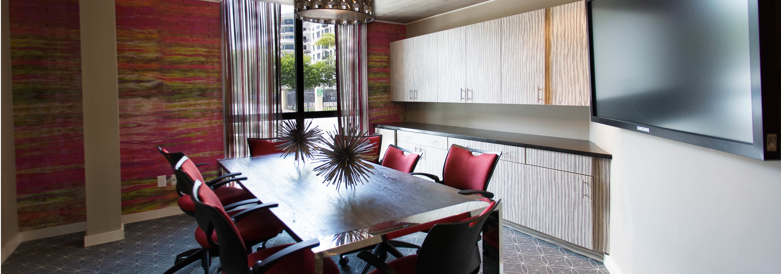Interior conference room space at AMLI Dadeland with rectangular conference table and chairs, mounted tv and modern decor