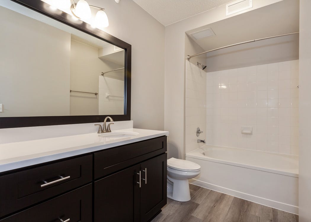 Interior of AMLI at Seven Bridges apartment bathroom with dark wood cabinets and white countertop and oval garden tub