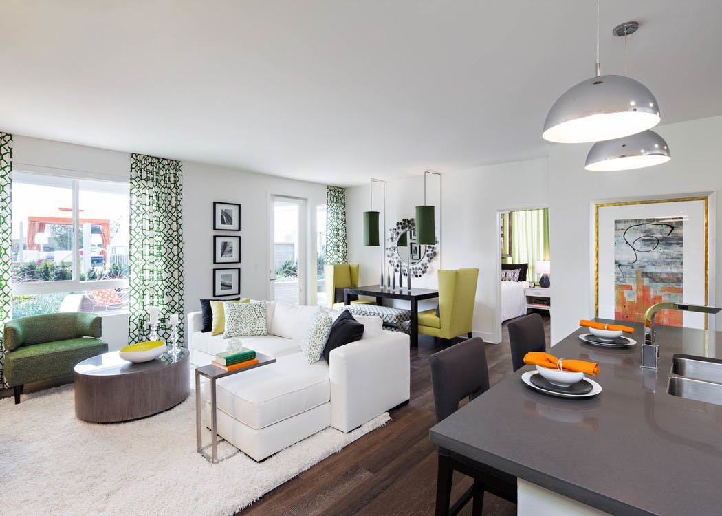 Interior of AMLI Lex on Orange furnished apartment living room with white couch and dining table in front of large windows