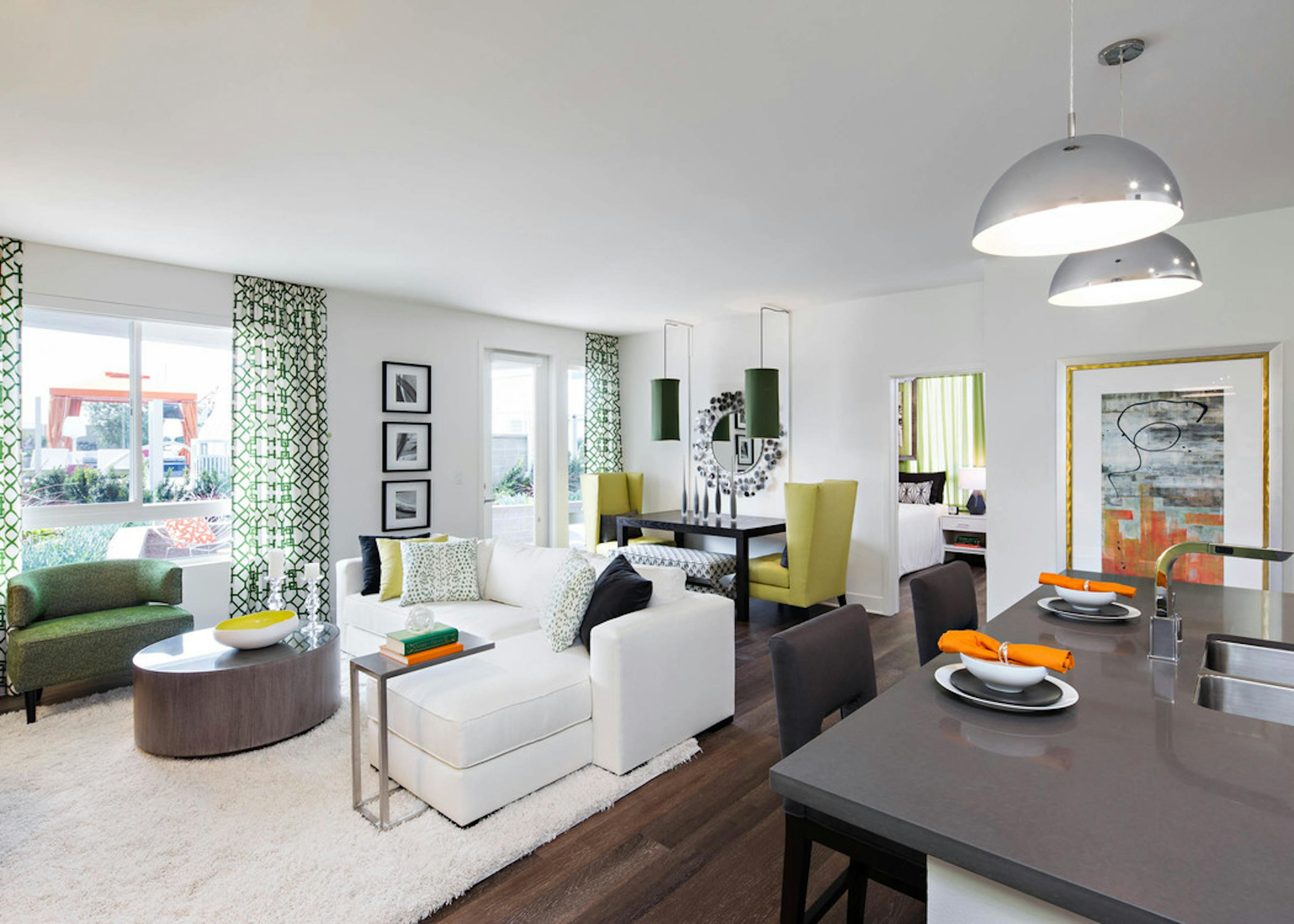 Interior of AMLI Lex on Orange furnished apartment living room with white couch and dining table in front of large windows