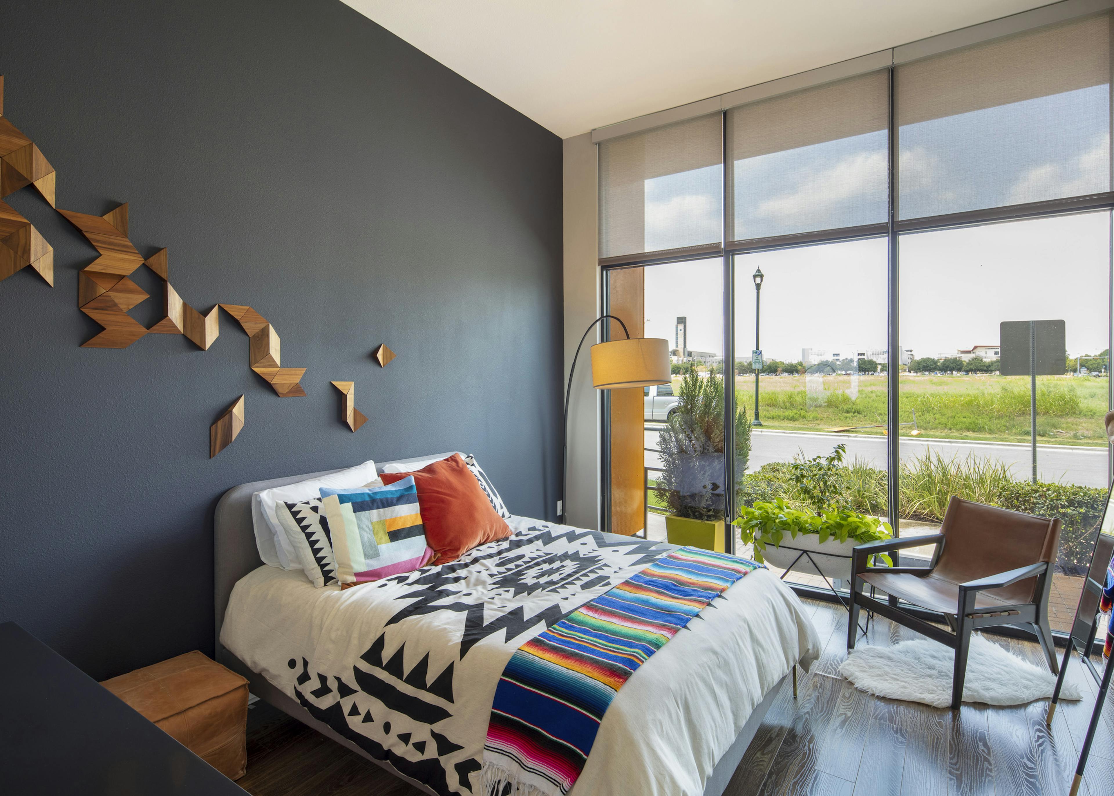 AMLI on Aldrich apartment bedroom with colorful bed on dark gray wall and floor to ceiling windows with view of green field
