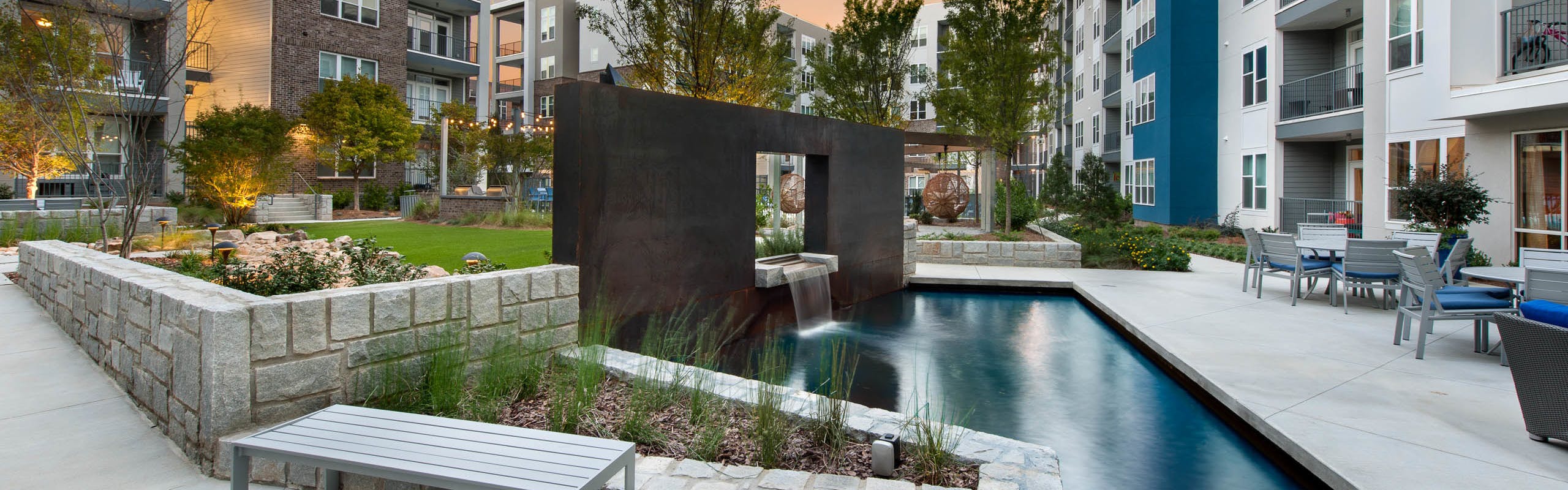 AMLI Piedmont Heights courtyard area with shallow stone walls lining pond with a waterfall and green grass in the background
