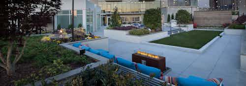 AMLI Arts Center rooftop firepit with a straight line of blue couches behind it and surrounding green landscaping